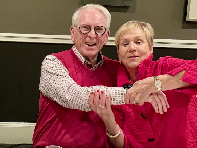 A pair of people posing for the camera in red attire.